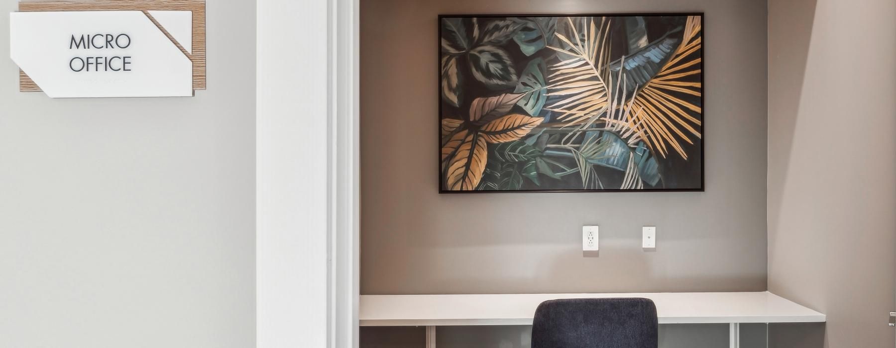a room with a desk, chair and a painting on the wall