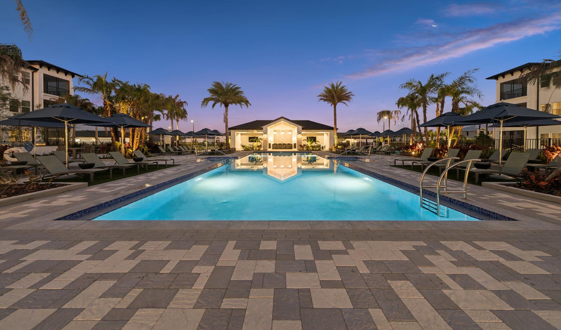 a pool with a deck and umbrellas by it